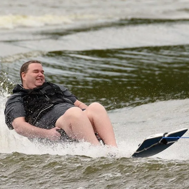 young male sit skier skiing around the lake with a big smile on his face