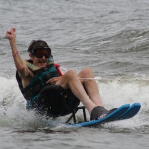 an adult male skier, sit skiing with his fist in the air and a HUGE smile on his face