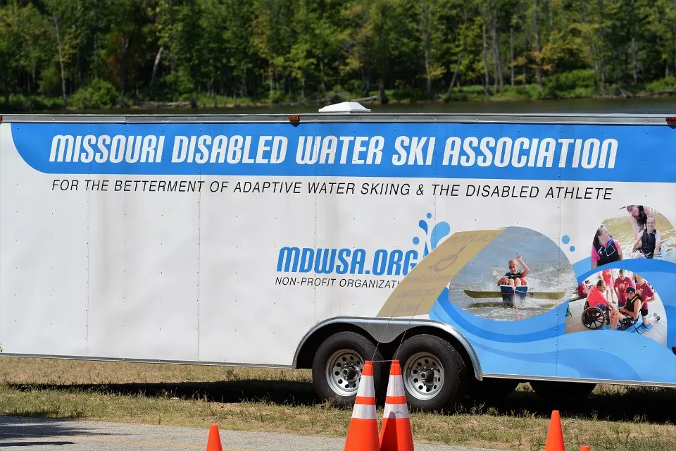DSC_7395 MDWSA equipment trailer has 3 photos on it; one of a sit skier in action, one of a skier having fun hanging out in the shallow part of the lake and one of a skier getting fitted for his ski equipment